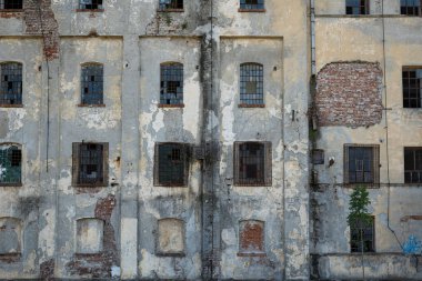 Harap olmuş bina cephesi. Çatlamış ve soyulmuş dış alçı tuğla duvar ve eski pencere çerçeveleri, insan yok..
