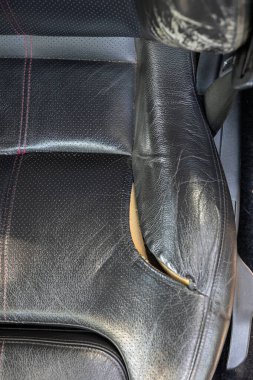 Yırtılmış ve yırtılmış doğal deri araba koltuğu. Hasarlı deri, açık köpük. Yakın çekim, insan yok.