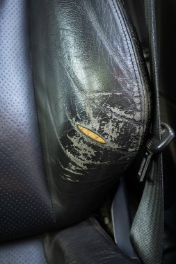 Yırtılmış ve yırtılmış doğal deri araba koltuğu. Hasarlı deri, açık köpük. Yakın çekim, insan yok.