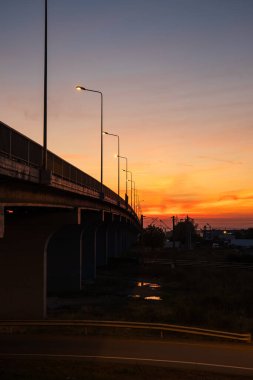 Alacakaranlıkta beton köprü silueti. Parlayan sokak lambası, geniş açı, insan yok.