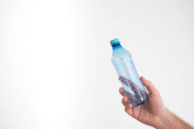Açık mavi, boş, şeffaf plastik şişe beyaz tenli bir erkeğin elinde.
