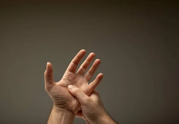 Caucasian man\'s hand isolated. Thumb pressure massaging inner open palm, chronic pain concept