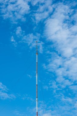 Uzun, yapılı telekomünikasyon anteni. Düşük açı, mavi gökyüzü, insan yok..