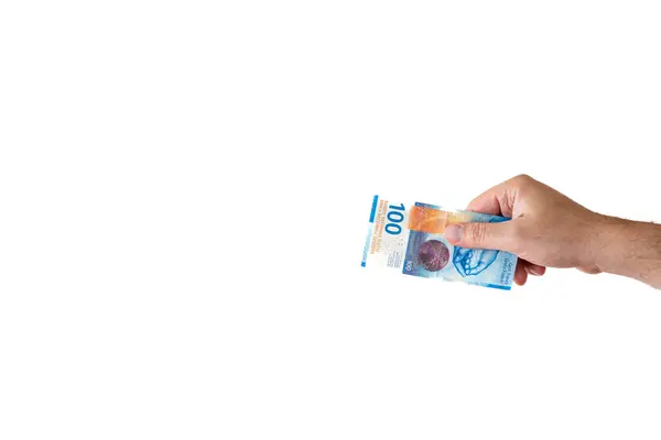 Stock image One one hundred Swiss francs cash banknote or bill held by Caucasian male hand. Close up studio shot, white background.