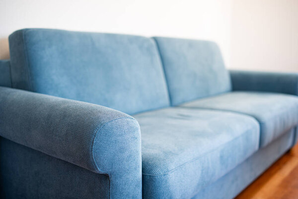 Light blue fabric sofa with inside apartment room. Close up, side view, shallow depth of field, no people