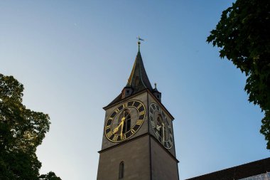 Zürih, İsviçre 'deki Aziz Peter Kilisesi. Güneşli yaz sabahı ışığı, alçak açılı sokak manzaralı kilise saat kulesi..