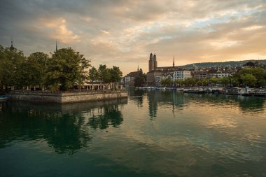 03-09-2024 Zurich, Switzerland. Touristic old part of town at sunrise. Summer dawn, famous cathedrals along the Limmat river promenade, dramatic cloudscape and water reflections. clipart