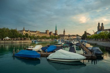 03-09-2024 Zürih, İsviçre. Güneşin doğuşunda şehrin eski turistik bir yerinde. Yaz şafağı, Limmat nehri boyunca ünlü katedraller dramatik bulutlar ve su yansımaları..