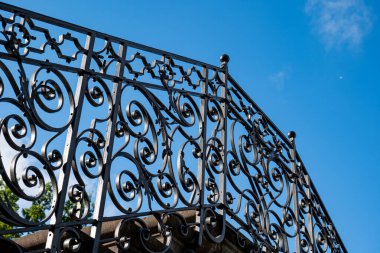 Demir balkon korkuluğu döşemiş. Yukarı bakıyorum, arkamda mavi gökyüzü var, insan yok..