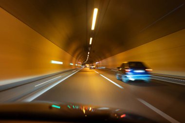 Aydınlatılmış bir yeraltı tünelinde bulanık arabalar. Yavaşlama hızı, trafikte arabalar, insan yok..