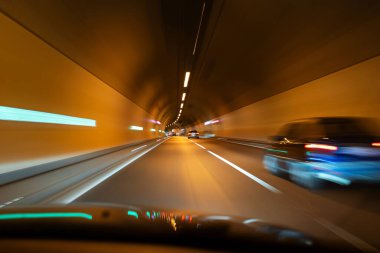 Aydınlatılmış bir yeraltı tünelinde bulanık arabalar. Yavaşlama hızı, trafikte arabalar, insan yok..