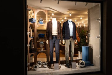 Mağaza vitrininde kadın mankenler gündelik sonbahar kış şık giysileri, gece sahnesi.