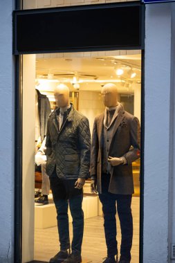 Erkek mankenler vitrin vitrininde gündelik sonbahar kıyafetleri giyerler. Kış şık giysileri, gece sahneleri..