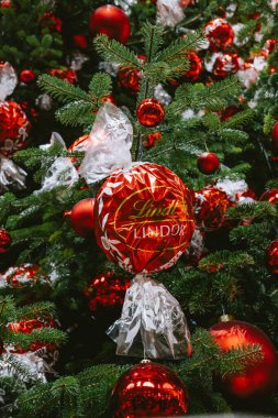 3-12-2024 Zurich, Switzerland. Large Christmas tree inside Zurich main station decorated with red Lindt chocolate balls. Close up, looking up shot, no people clipart