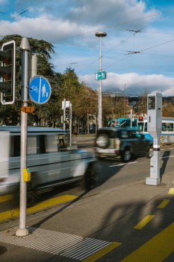 3-12-2024 Zurich, Switzerland. Blurred cars in traffic driving past a radar speed trap camera near Burkliplatz clipart