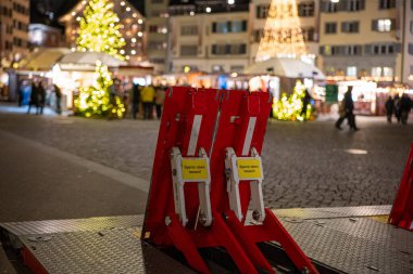 3-12-2024 Zürih, İsviçre. Büyük, kırmızı, katlanabilir mobil araç hafifletme engelleri Noel pazarı girişinde, akşam geç saatlerde.