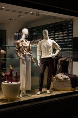 Mağaza vitrininde kadın ve erkek mankenler gündelik sonbahar kıyafetleri giyerler. Kış şık elbiseler, gece sahneleri.