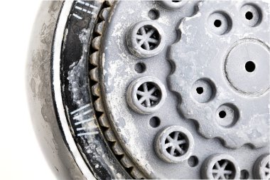 Silver round shower head with hard water deposit all around the sprinklers close up macro side shot isolated against white backdrop clipart