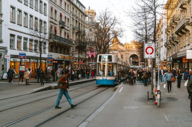 17-12-2024 Zürih, İsviçre. 11 numaralı tramvay ana istasyon yakınlarındaki Bahnhofstrasse istasyonundan yolcu alıyor. Güneşli bir kış akşamı, yayalar.