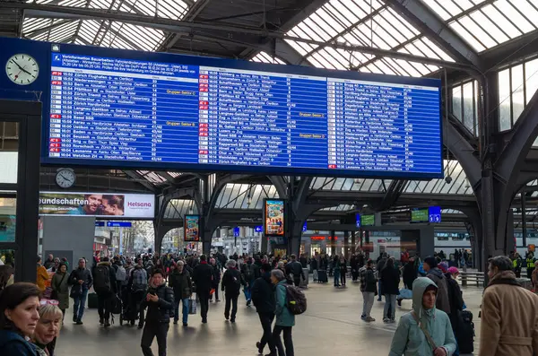 17-12-2024 Zürih, İsviçre. Hauptbahnhof tren istasyonunun iç mekanı genel bina, aydınlatılmış zaman çizelgesi ve kalabalıkla dolu.