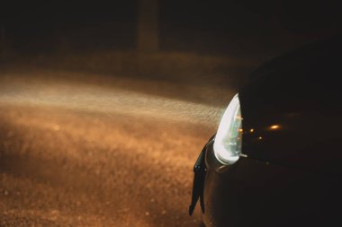 Gece vakti boş bir yolda yoğun bir kış sisinin su parçacıklarını aydınlatan araba ksenon farları. Yaklaş, karamsar, insan yok..