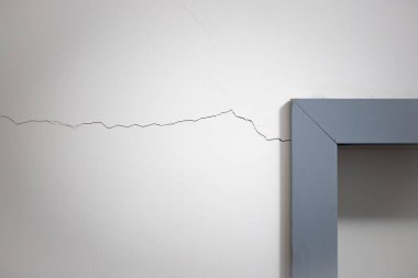 Kapı çerçevesinin yanındaki beyaz duvarda çatlak var, insan yok..