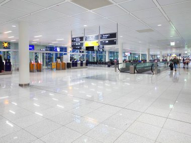 27-12-2024 Munich International Airport, Germany. People walking or waiting on the lounge area near departure gates. clipart