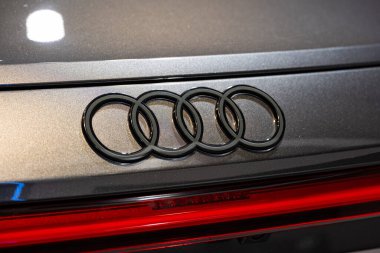 Audi marka araba yeni bir arabanın arkasında amblem ya da logo var. Karanlık, gölge çizgileri, iç çekimler, insan yok..