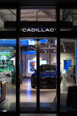 20-03-2023 Zürih, İsviçre. Geceleri Cadillac galerisi girişi. Aydınlatılmış marka logosu ya da işareti, mavi, elektrikli Lyriq sergi salonunun zemininde. Dışarıya bakan kimse yok..