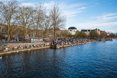 05-04-2025 Zürih, İsviçre. Turist kalabalığı ilk bahar günlerinin ve Bellevue göl kenarındaki gezinti alanında güneşli havanın tadını çıkarıyor..