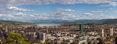 16-05-2025 Zürih, İsviçre. Yukarıdan tepeden bakıldığında panoramik bir manzara. Bulutlu gökyüzü, karlı Alpler ve arka planda Zürih Gölü.