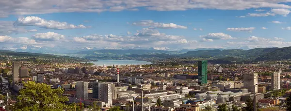 16-05-2025 Zürih, İsviçre. Yukarıdan tepeden bakıldığında panoramik bir manzara. Bulutlu gökyüzü, karlı Alpler ve arka planda Zürih Gölü.