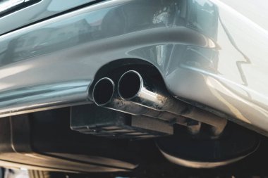 İkiz uçlu ya da çift egzozlu, krom renkli araba kuyruk borusu yakın çekim. Düşük açı, insan yok.