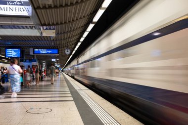 30-06-2025 Zürih, İsviçre. Bulanık, giden tren ve metro istasyonundaki insanlar ya da HB platformu. Geniş açı görünümü, yapay aydınlatma