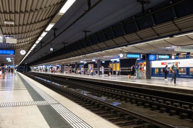 30-06-2025 Zürih, İsviçre. Tren ve insanlar yeraltı ana istasyonunda ya da HB platformunda bekliyorlar. Geniş açı görünümü, yapay aydınlatma