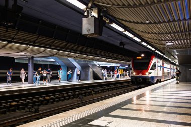 30-06-2025 Zürih, İsviçre. S5 yolcu treni yeraltı ana istasyon peronundan kalkmak üzere. Geniş açı açısı, rayların kenarında bekleyen insanlar.