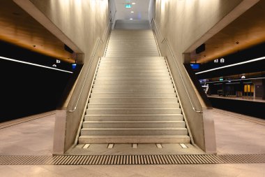 30-06-2025 Zürih, İsviçre. Geniş, boş merdivenler, metro istasyonunun içinde parmaklıklar var. Yapay aydınlatma, geniş açı görünümü, insan yok.