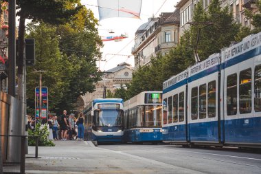 30-06-2025 Zürih, İsviçre. Bahnhofstrasse tramvay istasyonunda turistler, banliyö ve tramvaylar.
