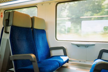 Avrupa 'da bir yolcu treninde boş pencere koltukları. Bulanık, parlak dış görünüş, geniş açı, insan yok.