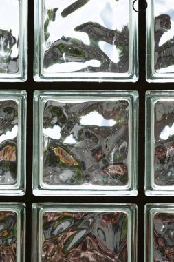 Güneş ışığının parıldadığı mat bir cam duvar örüyor. Ayrıntılı çekim, insan yok.