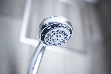 Kullanılmış, limon pullu ve sert su lekeli bir duş başlığı. Yakın çekim, parlak, doymamış renkler, insan yok.