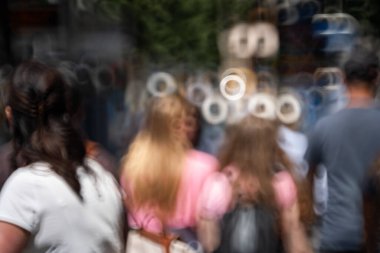 Bulanık, bulanık, tanınmayan insanlar ya da kalabalık bir şehir kaldırımında yayalar. Güneşli yaz günü, donut şeklinde bokeh