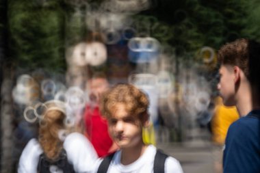 Bulanık, bulanık, tanınmayan insanlar ya da kalabalık bir şehir kaldırımında yayalar. Güneşli yaz günü, donut şeklinde bokeh