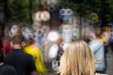 Bulanık, bulanık, tanınmayan insanlar ya da kalabalık bir şehir kaldırımında yayalar. Güneşli yaz günü, donut şeklinde bokeh