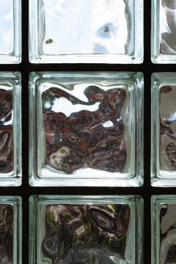 Güneş ışığının parıldadığı mat bir cam duvar örüyor. Ayrıntılı çekim, insan yok.