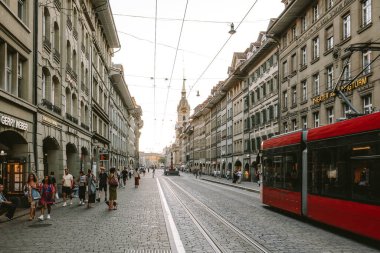 07-08-2025 Bern, İsviçre. Barenplatz istasyonu yakınlarındaki Spitalgasse 'de kırmızı tramvay ve turistler. Güneşli yaz akşamı, geniş açı manzaralı.
