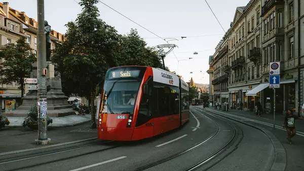 07-08-2025 Bern, İsviçre. 8 numaralı tramvay ana tren istasyonuna yakın bir istasyondan ayrılıyor. Yaz akşamı ışığı, gün batımından sonra geniş açı manzarası.