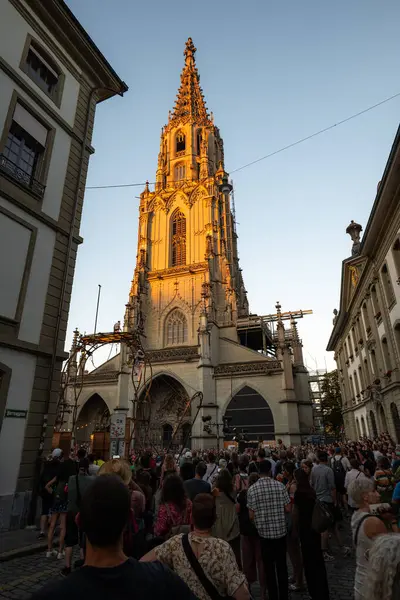07-08-2025 Bern, İsviçre. Bern sokaklarının ünlü Katedrali 'nin yakınında bir sürü insan var. Geniş açılı çekim, güneşli yaz günbatımı ışığı