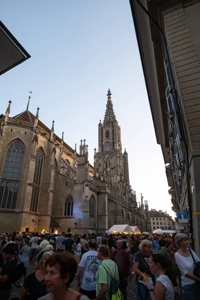 07-08-2025 Bern, İsviçre. Bern sokaklarının ünlü Katedrali 'nin yakınında bir sürü insan var. Geniş açılı çekim, güneşli yaz günbatımı ışığı