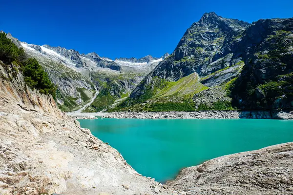 07-08-2025 Handegg, İsviçre. Handegg 'deki Gelmer Gölü veya Gerlmersee Gölü' nün güzel turkuaz suyu. Geniş açı, güneşli yaz günü, mavi gökyüzü, arka planda Alpler, insan yok.